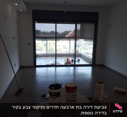 חדר עם דלי צבע וכלי עבודה על הרצפה